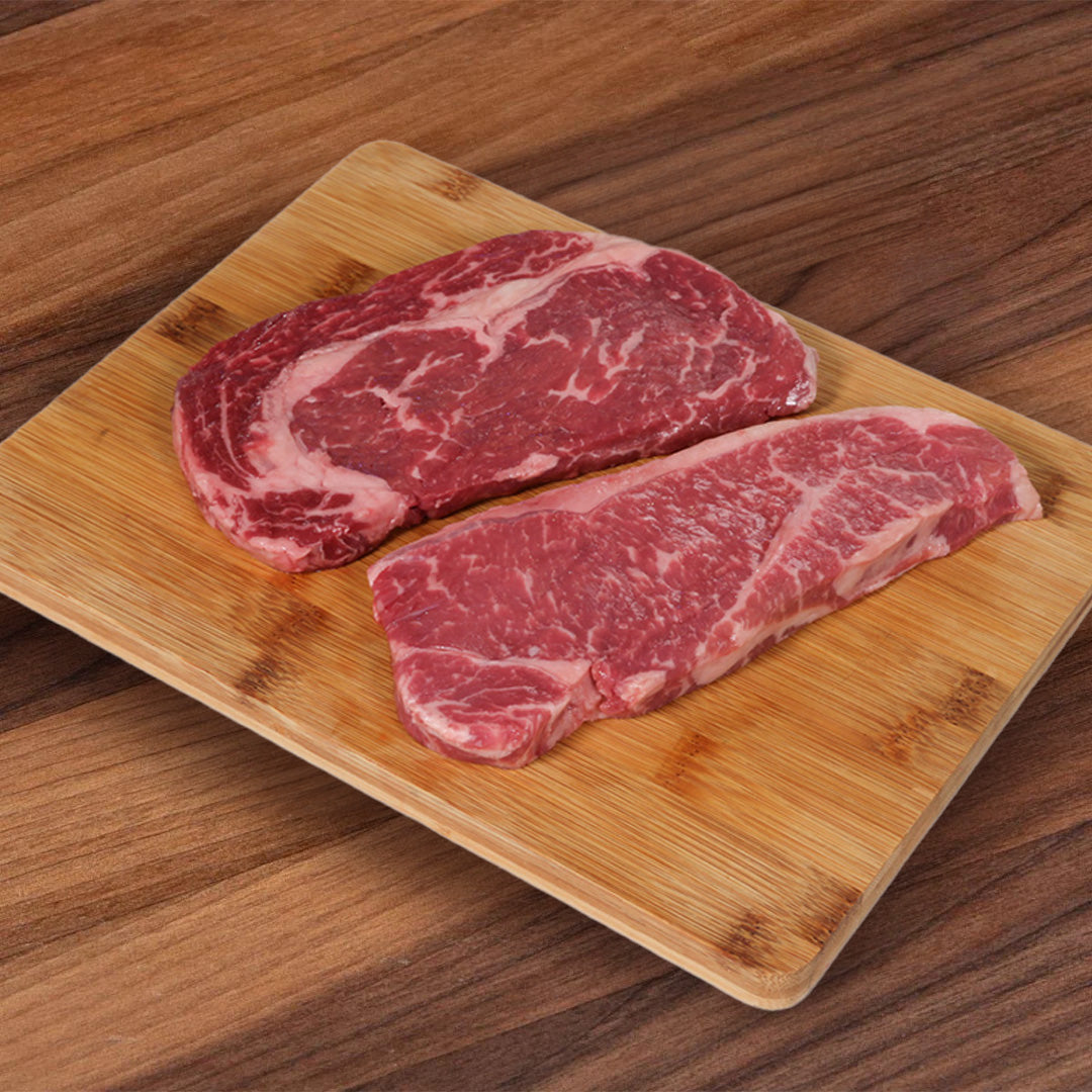 Prime Black Angus beef steak set: two marbled cuts on bamboo cutting board