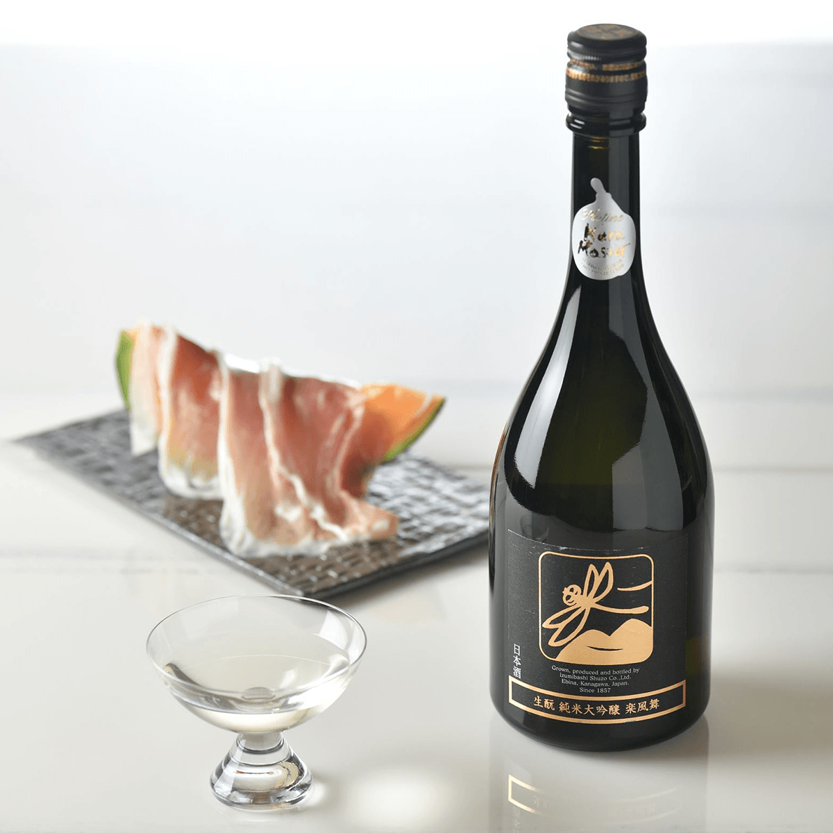 Junmai daiginjo sake bottle with gold label, shown with tasting cup
