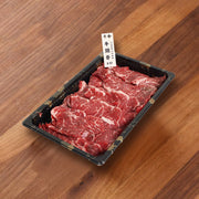 Raw marbled chuck flap tail beef slices in a black hot pot tray