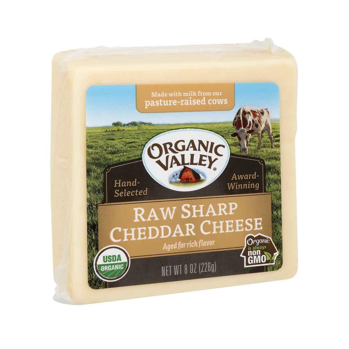 Packaged raw sharp cheddar cheese, pale yellow block in square wrap.