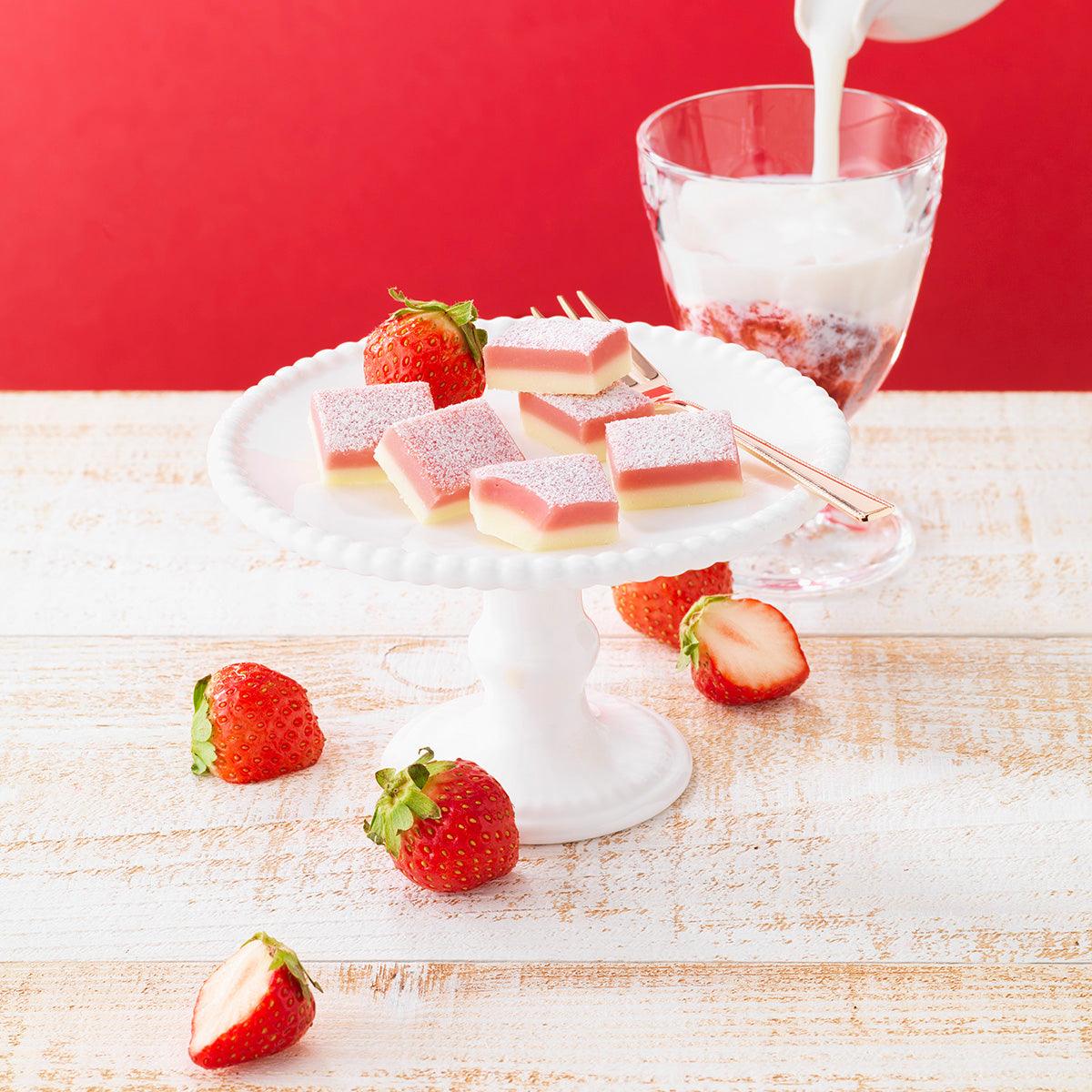 Strawberry milk nama chocolate squares on plate with fresh strawberries and glass