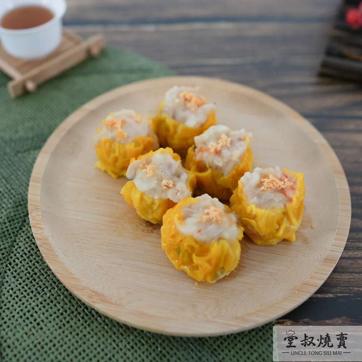Pork siu mai dumplings on wooden plate, yellow wrappers with white tops