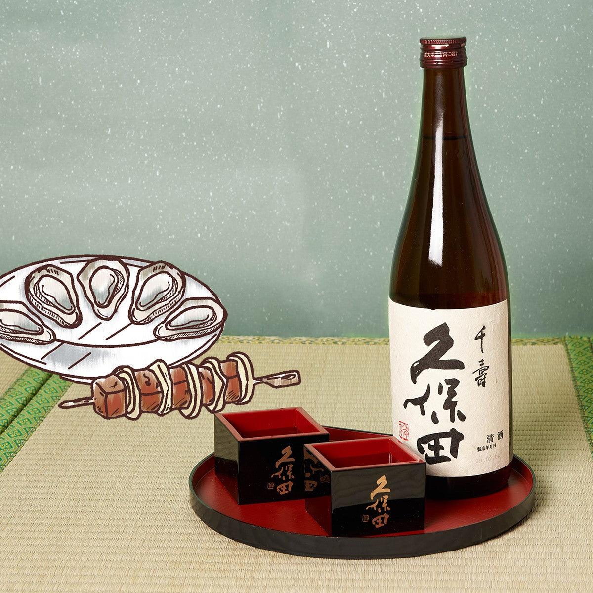 Amber sake bottle with label and matching sake cups on black and red tray