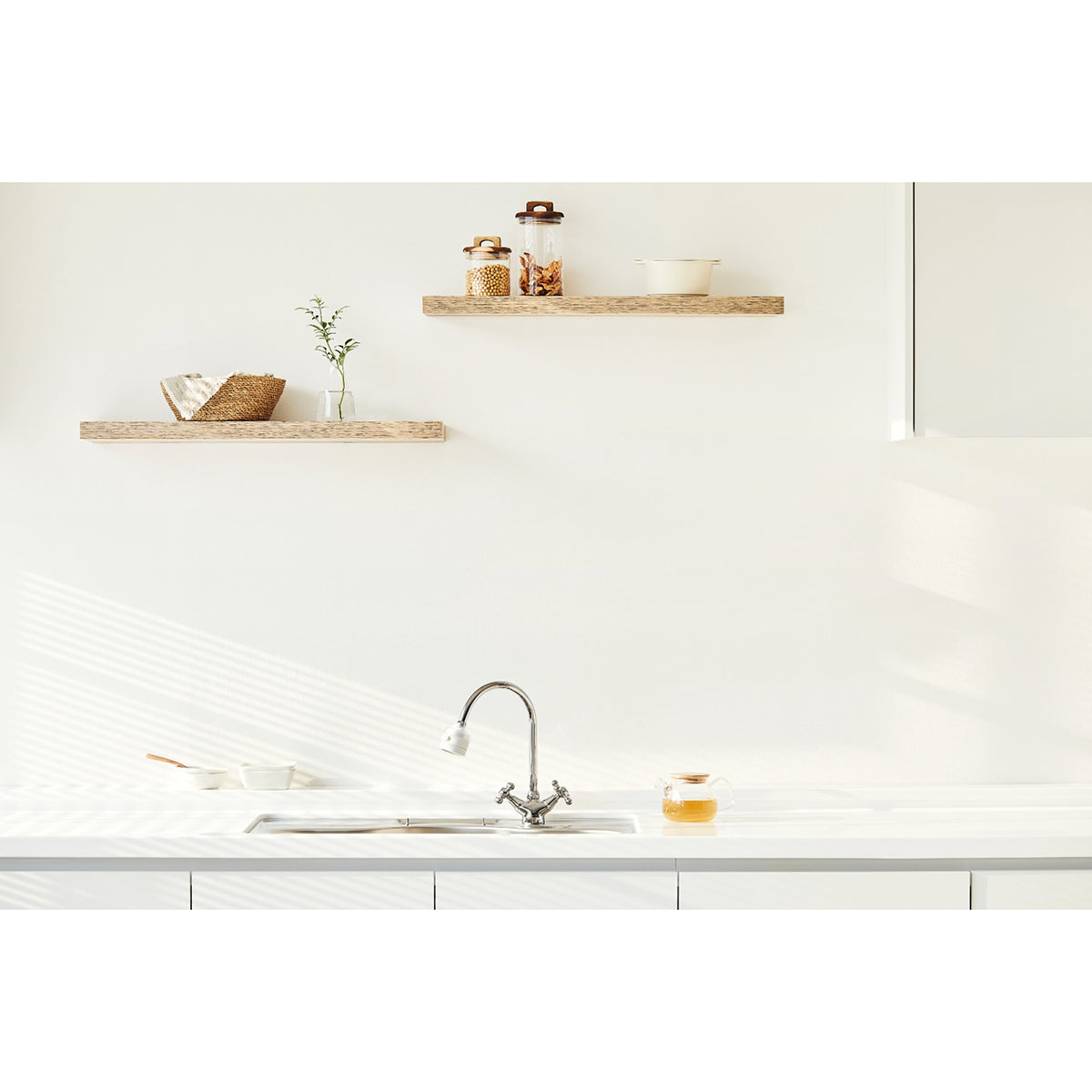 Chrome kitchen faucet with attached handheld shower head over white sink