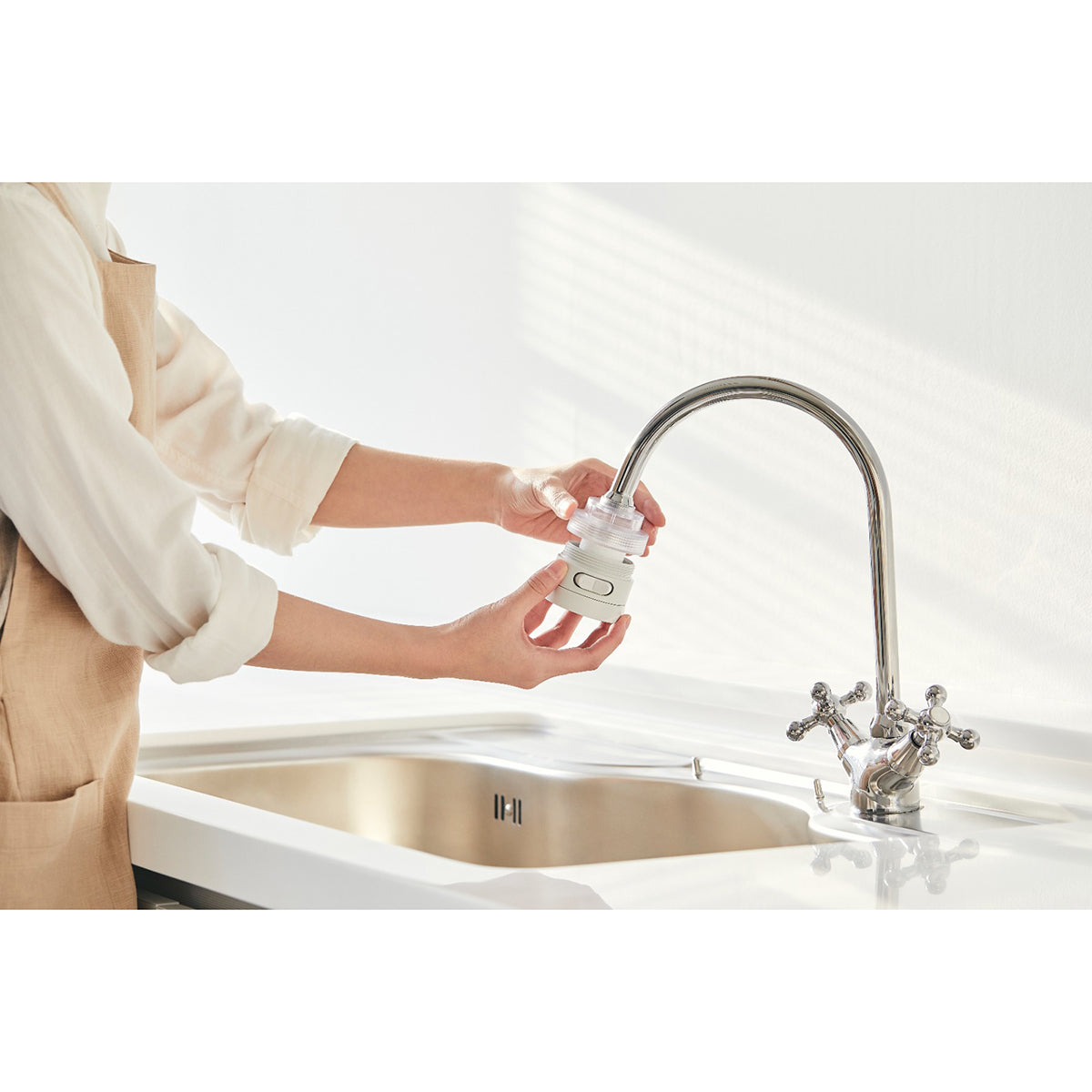 Kitchen shower head filter cap held in hand at chrome sink faucet