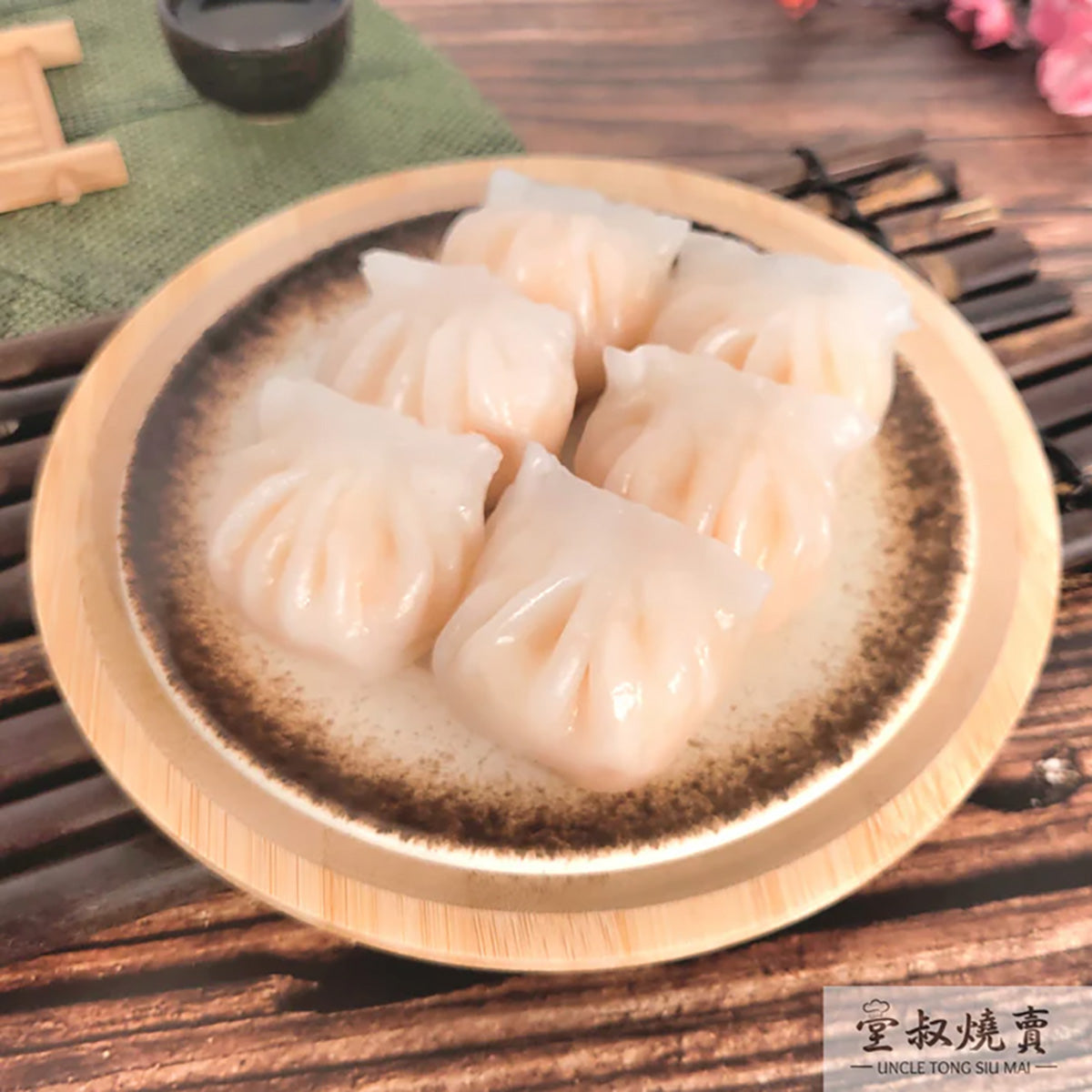 Steamed shrimp siu mai dumplings in a wooden tray, four pale translucent pieces