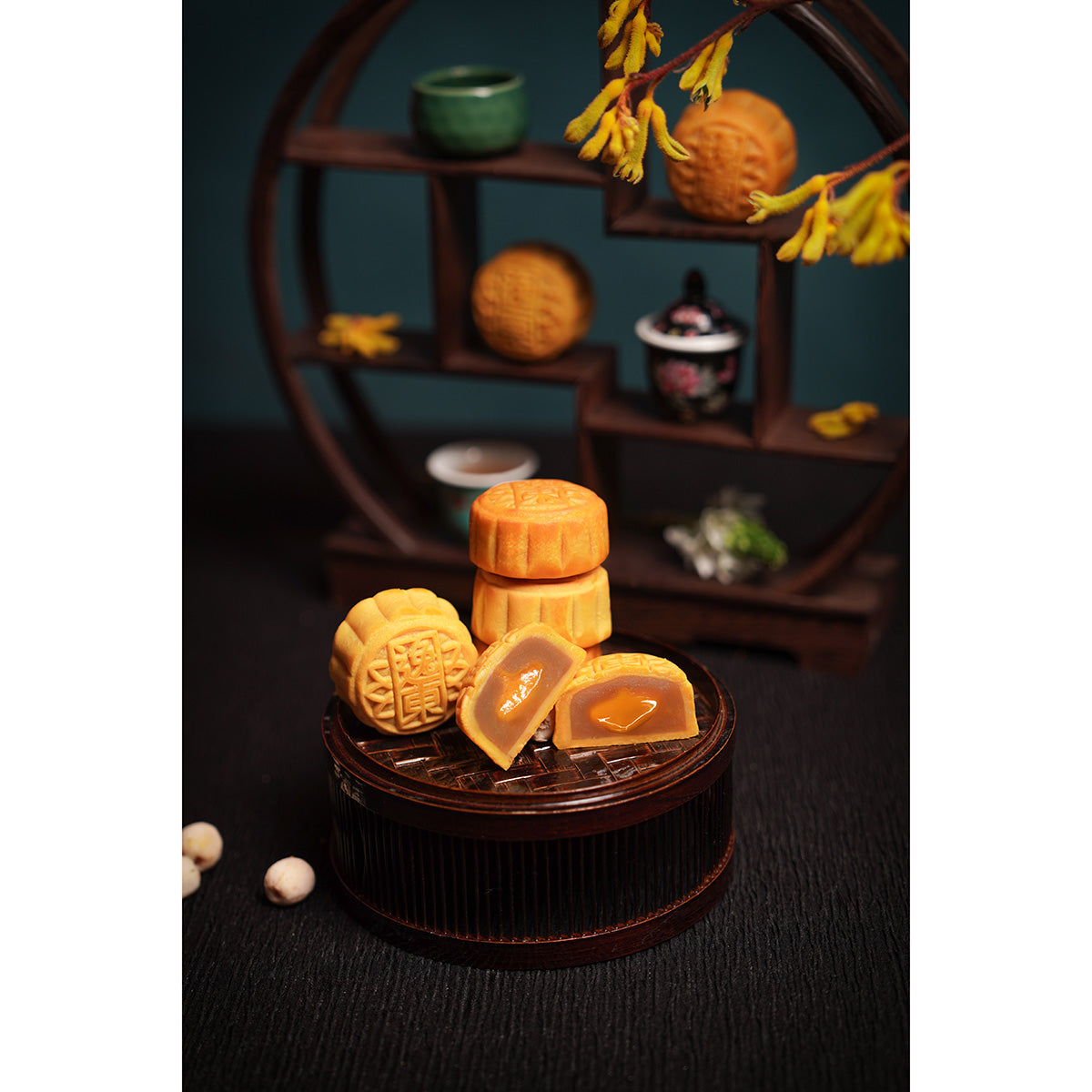 Mini mooncakes on a dark round container with a wooden display behind