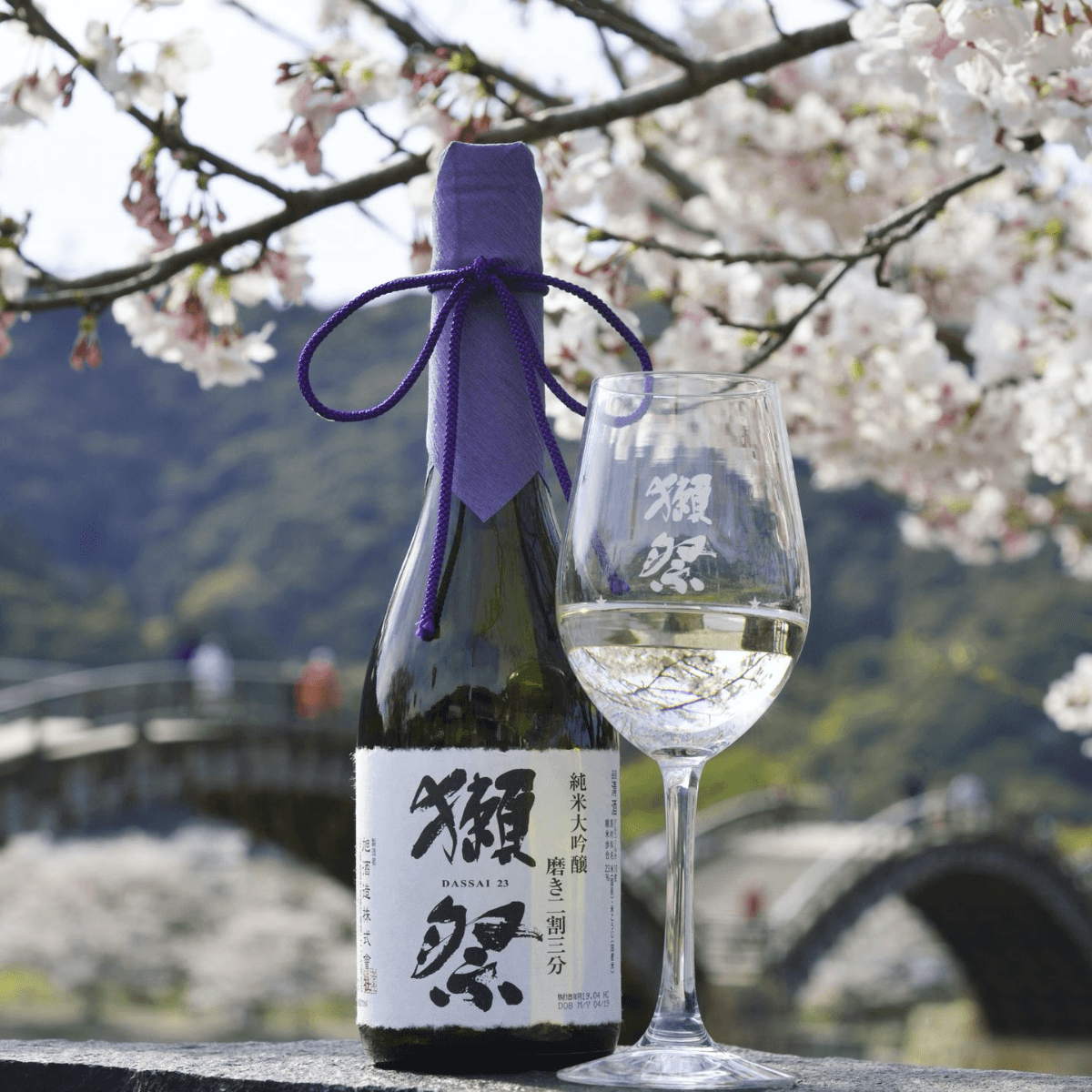 DASSAI 23 sake bottle with blue wrap and wine glass of clear liquid